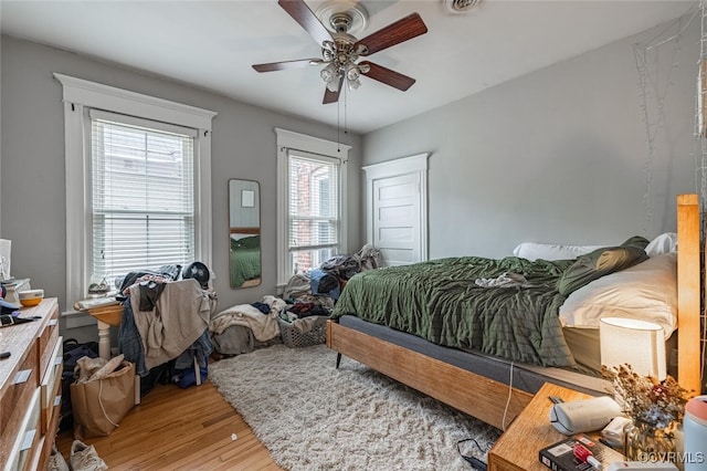 bedroom with multiple windows, ceiling fan, and hardwood / wood-style floors