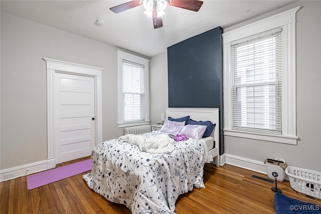 bedroom featuring hardwood / wood-style floors, radiator heating unit, and ceiling fan