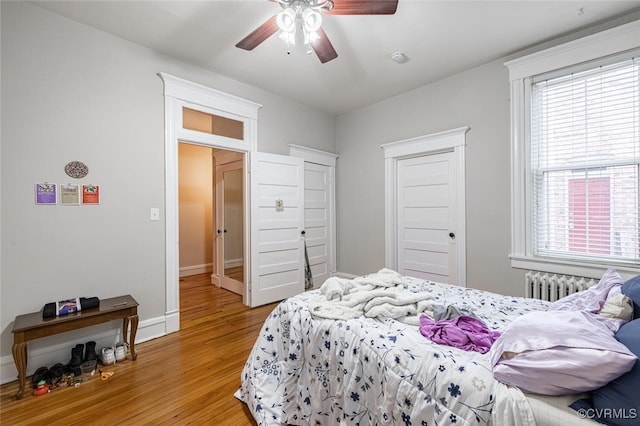 bedroom featuring radiator heating unit, light hardwood / wood-style floors, and ceiling fan