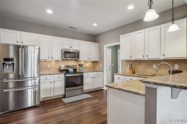 kitchen featuring pendant lighting, white cabinets, light stone countertops, dark hardwood / wood-style flooring, and stainless steel appliances