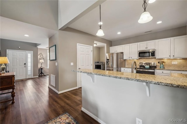 kitchen featuring a kitchen breakfast bar, white cabinets, pendant lighting, and appliances with stainless steel finishes