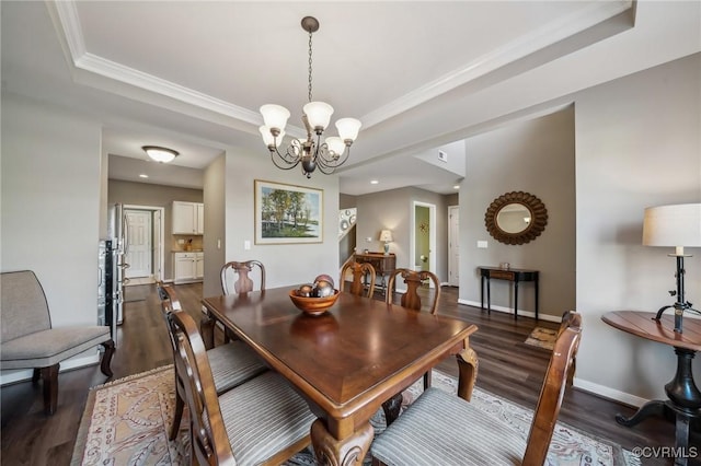 dining area with a tray ceiling, dark hardwood / wood-style flooring, a chandelier, and ornamental molding