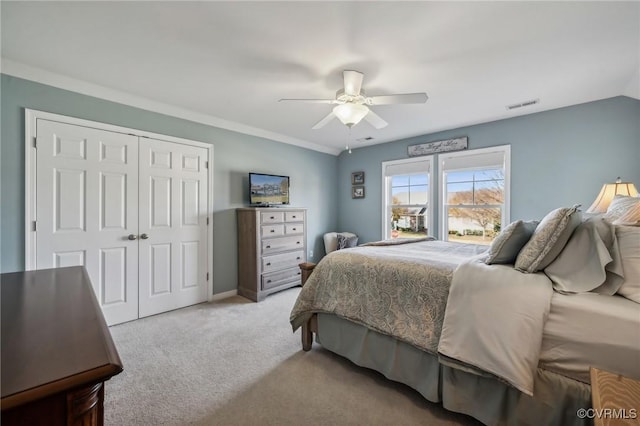 bedroom with vaulted ceiling, ceiling fan, ornamental molding, light colored carpet, and a closet