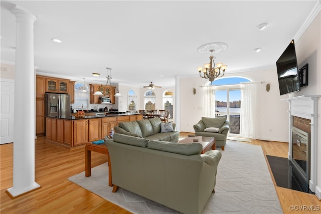 living room featuring decorative columns, crown molding, a fireplace, and light hardwood / wood-style floors