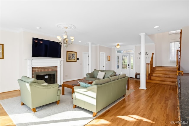 living room featuring hardwood / wood-style flooring, crown molding, ornate columns, and a fireplace