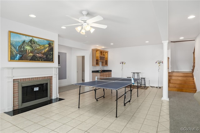 game room featuring sink, ceiling fan, light tile patterned floors, a fireplace, and decorative columns