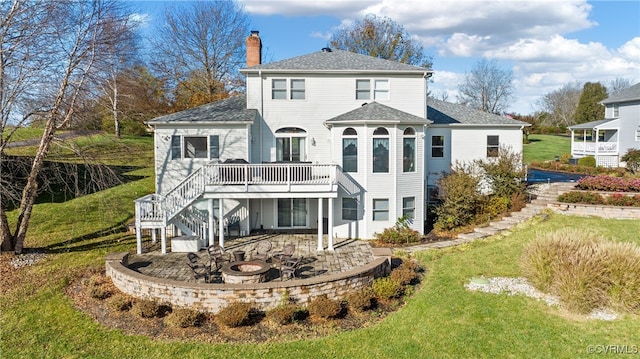 back of property with a yard, a patio, a deck, and an outdoor fire pit