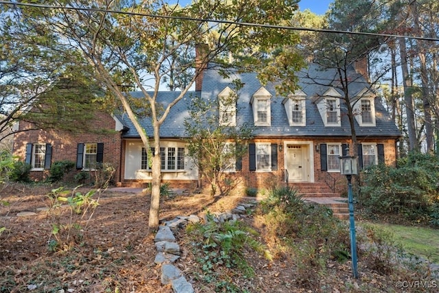 view of front of house with a chimney and brick siding