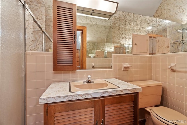 full bathroom with vanity, tile walls, toilet, and an enclosed shower