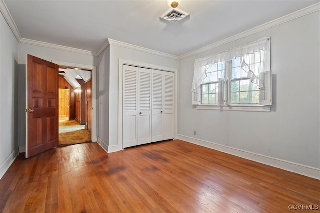 unfurnished bedroom featuring visible vents, baseboards, hardwood / wood-style floors, and crown molding