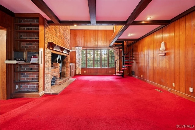 unfurnished living room featuring beam ceiling, wood walls, a fireplace, and carpet