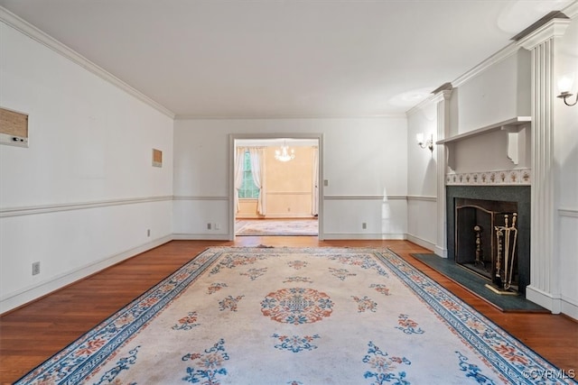 unfurnished living room with a fireplace with raised hearth, baseboards, wood finished floors, and crown molding