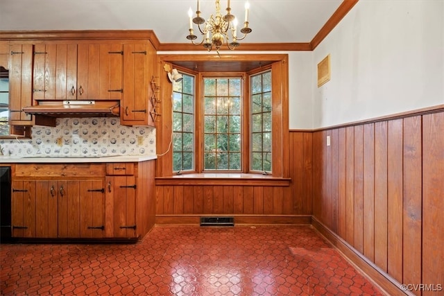 kitchen with brown cabinets, a wainscoted wall, visible vents, and pendant lighting