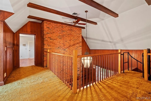 hall featuring lofted ceiling with beams, brick wall, wooden walls, and visible vents