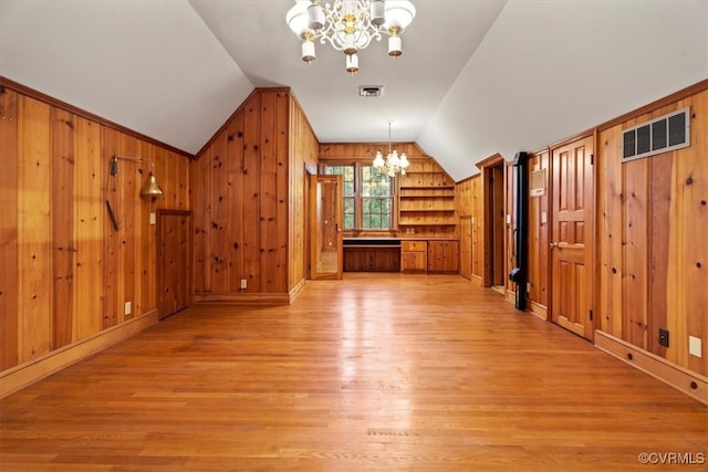 bonus room with visible vents, vaulted ceiling, wooden walls, a chandelier, and light wood-type flooring