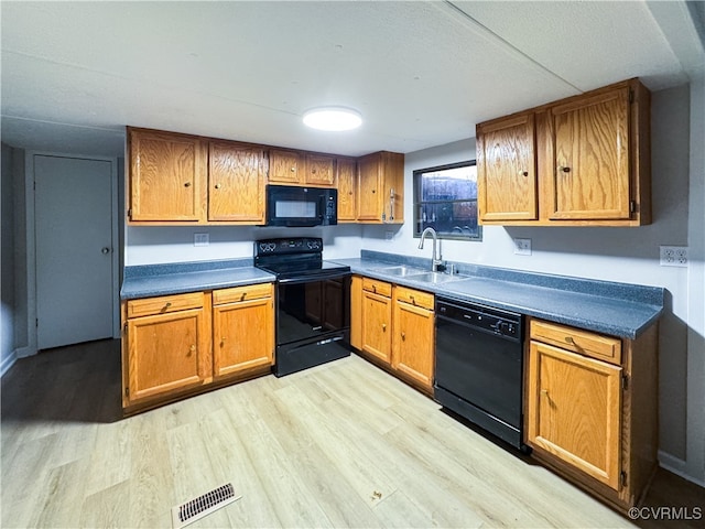 kitchen with black appliances, sink, and light hardwood / wood-style flooring