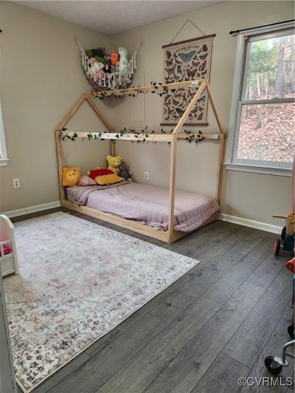 bedroom with dark hardwood / wood-style flooring and multiple windows