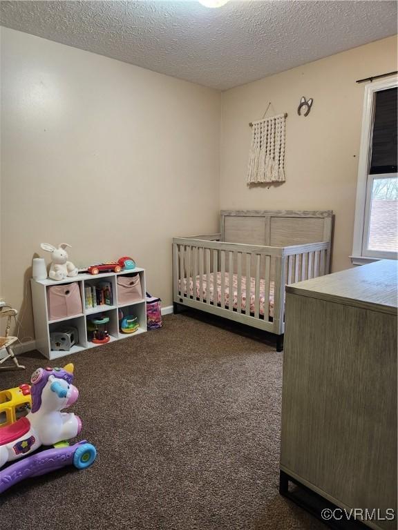 bedroom with a textured ceiling, carpet floors, and a crib