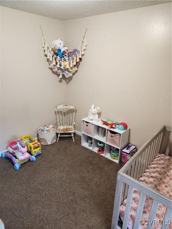 carpeted bedroom featuring a textured ceiling and a crib