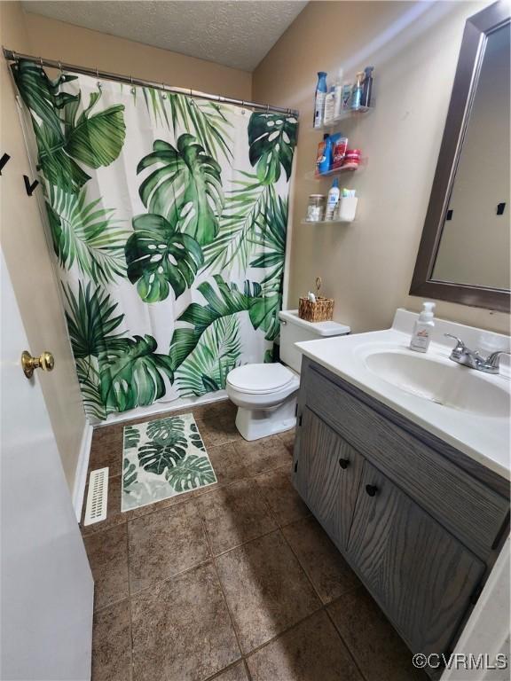 bathroom featuring a textured ceiling, toilet, and vanity