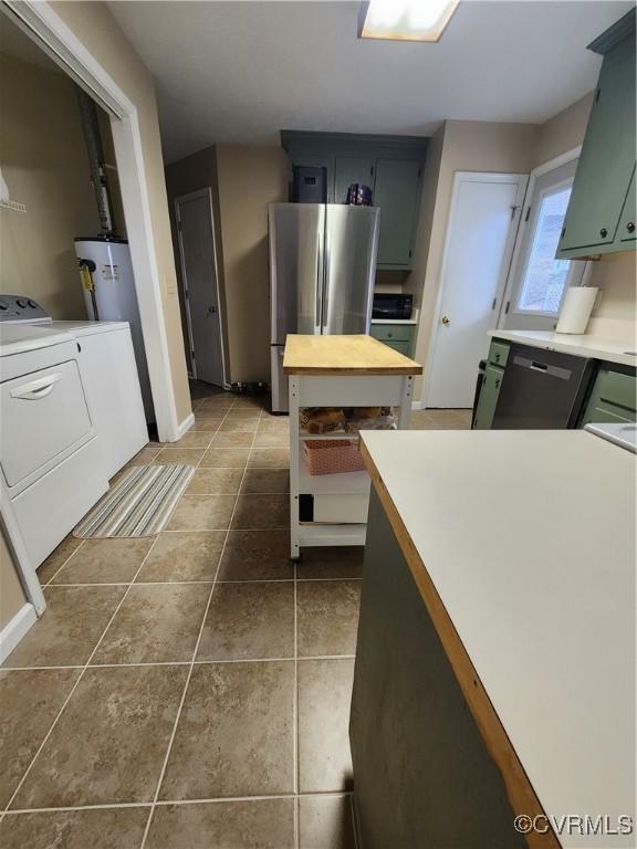 kitchen featuring water heater, washer and clothes dryer, stainless steel fridge, dishwasher, and dark tile patterned floors