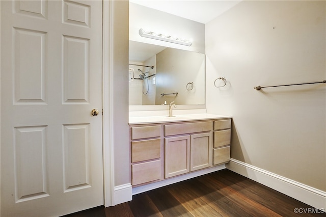 bathroom featuring baseboards, walk in shower, wood finished floors, and vanity