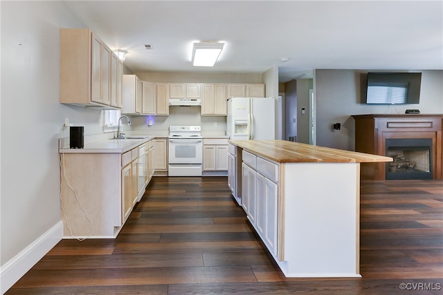 kitchen featuring dark wood-type flooring, white appliances, a sink, and under cabinet range hood