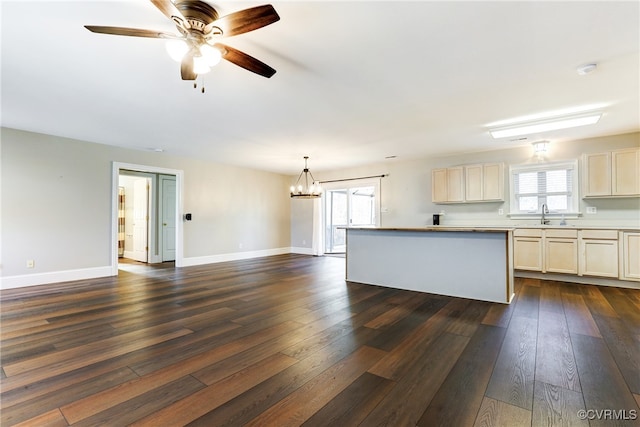 kitchen with dark wood-style floors, light countertops, a sink, and baseboards