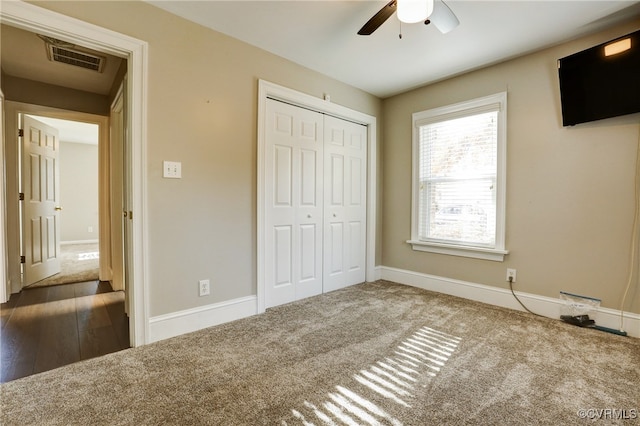 unfurnished bedroom with a ceiling fan, visible vents, baseboards, a closet, and dark carpet