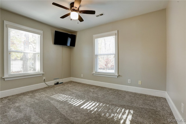 carpeted spare room with ceiling fan, visible vents, and baseboards