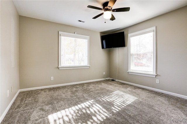 empty room featuring light carpet, plenty of natural light, visible vents, and baseboards