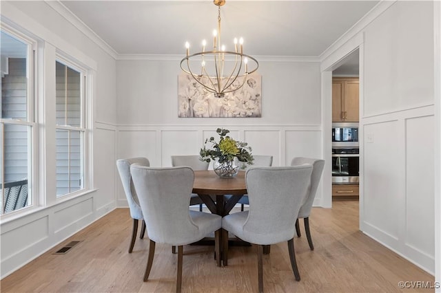 dining space featuring light hardwood / wood-style flooring, crown molding, and a notable chandelier