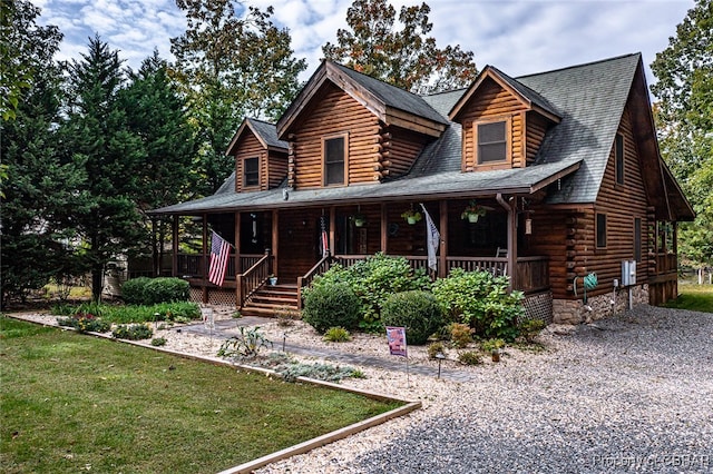 log cabin with covered porch and a front lawn