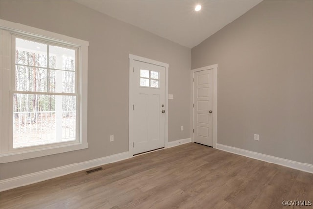 foyer entrance with vaulted ceiling and wood-type flooring