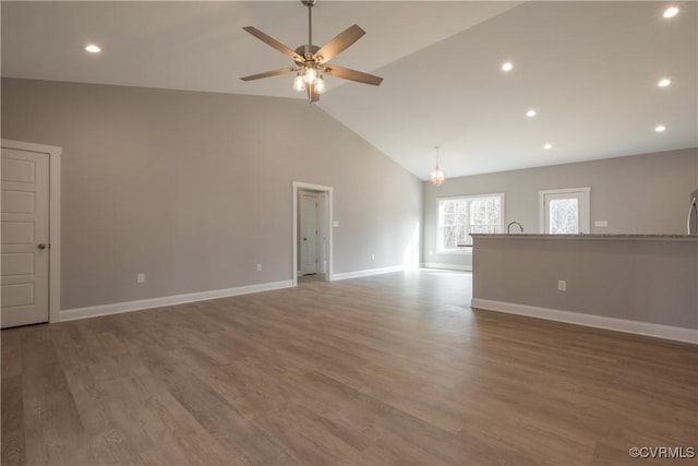 unfurnished living room featuring high vaulted ceiling, dark wood-type flooring, and ceiling fan