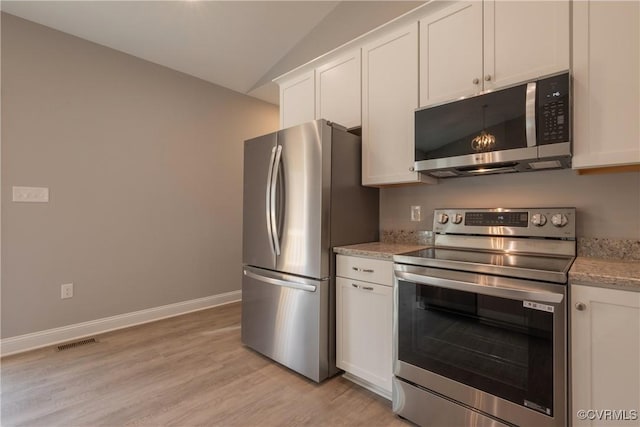 kitchen featuring lofted ceiling, white cabinetry, light stone counters, light hardwood / wood-style flooring, and stainless steel appliances