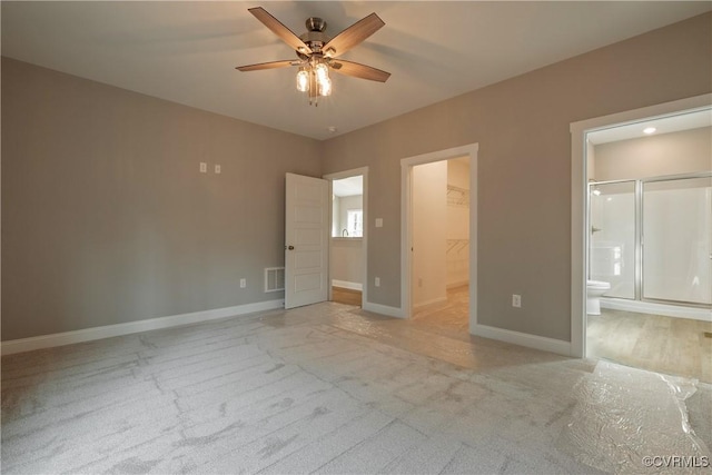 unfurnished bedroom featuring ceiling fan, connected bathroom, light carpet, and a spacious closet