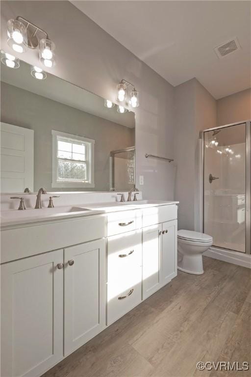 bathroom with hardwood / wood-style flooring, vanity, toilet, and walk in shower