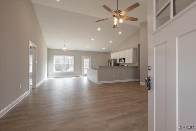 unfurnished living room featuring wood-type flooring, sink, ceiling fan, and high vaulted ceiling