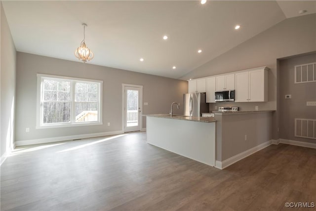 kitchen featuring stainless steel appliances, wood-type flooring, hanging light fixtures, and white cabinets