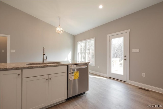 kitchen with sink, light stone counters, hanging light fixtures, stainless steel dishwasher, and white cabinets