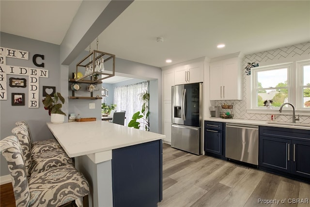 kitchen featuring kitchen peninsula, appliances with stainless steel finishes, sink, white cabinetry, and a breakfast bar area