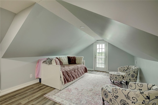 bedroom featuring access to exterior, wood-type flooring, and lofted ceiling