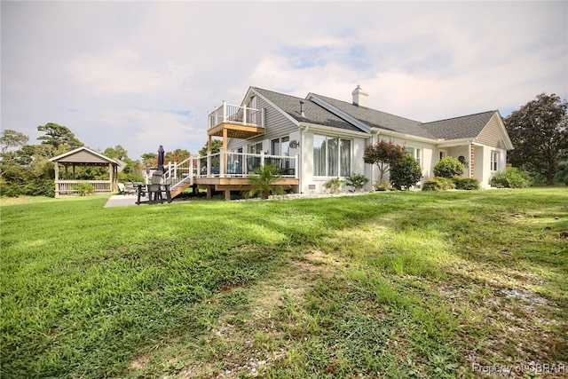 rear view of house with a gazebo, a deck, and a lawn