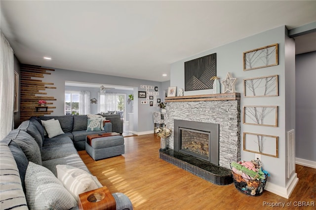 living room with hardwood / wood-style flooring, ceiling fan, and a fireplace