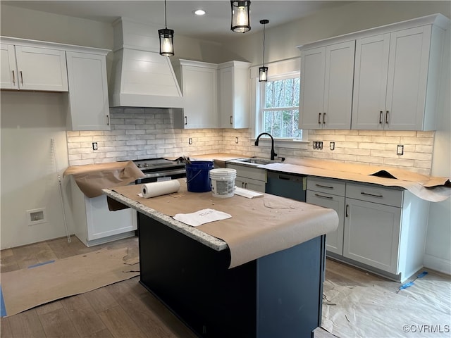 kitchen featuring light wood-type flooring, sink, pendant lighting, white cabinets, and a kitchen island