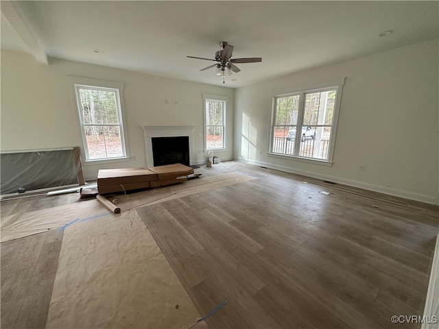 unfurnished living room featuring ceiling fan, plenty of natural light, and hardwood / wood-style floors