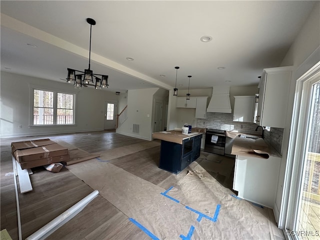 kitchen featuring a center island, decorative light fixtures, hardwood / wood-style flooring, white cabinets, and custom exhaust hood