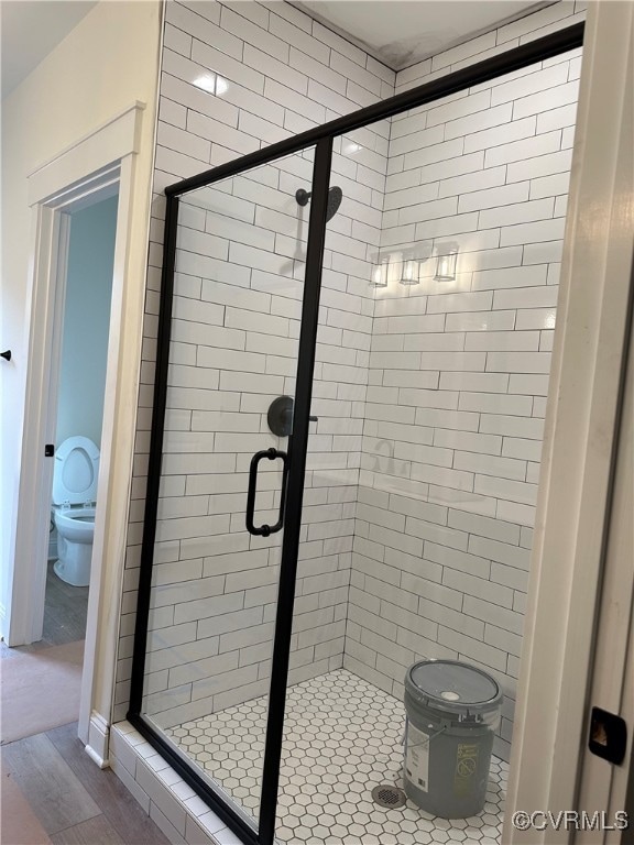 bathroom featuring a shower with door, wood-type flooring, and toilet