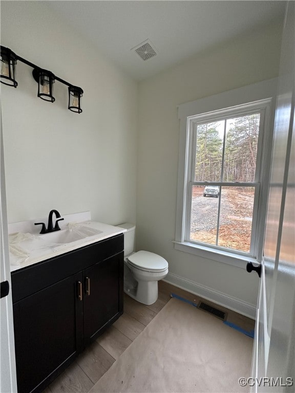 bathroom featuring vanity, hardwood / wood-style flooring, toilet, and a wealth of natural light